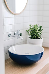 Fototapeta premium Modern luxury bathroom interior in navy blue and gold and white colors with modern bathroom sink setup featuring a sleek faucet, a round basin.