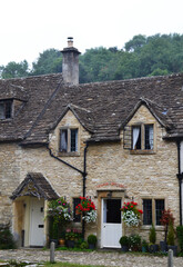 Charming stone cottage decorated with flowers in Castle Combe, Cotswolds, Wiltshire, UK