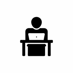 A man is sitting at a desk with a laptop. He is wearing a shirt and has a laptop on his lap