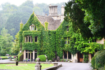 An old house covered in ivy. Castle Combe, Cotswolds, Wiltshire, England, UK