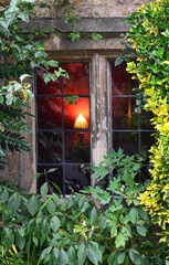 Close up picture of an old wooden window framed with ivy on a facade of a rural cottage in Castle Combe Village, Cotswold
