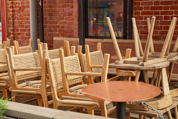 Overturned wooden chairs on tables in an outdoor cafe.