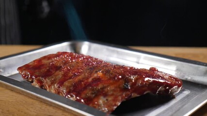 Slow motion flames caramelizing glazed bbq ribs on metal tray, searing meat surface with intense culinary technique and dramatic fire effect. Cooking in restaurant kitchen. High cuisine. Full hd