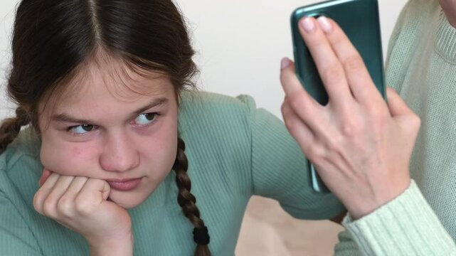 Mother scolding her daughter for viewing inappropriate content on phone. Mom telling kid girl about phone scam. Children and smartphone concept