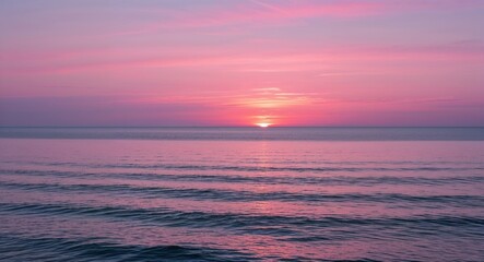 Fototapeta premium Sunset over calm ocean with soft pink skies background