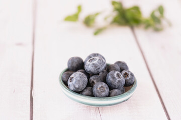Fresh blueberries resting in small bowl on white wooden table