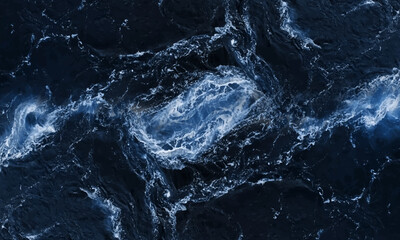 A monochrome top view on breaking waves , waves on a rocky seashore. Black and white sea.