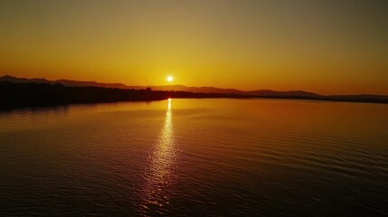 Golden Sunset Over Calm Waters With Mountain Silhouettes On The Horizon
