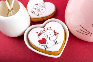 red heart-shaped lollipops in a white vase for Valentine's Day on a red and pink background, pink cup with a heart, festive still life, sweet gift for Valentine's Day