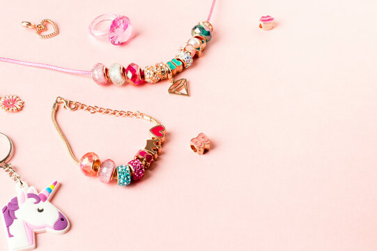 Charm Bracelets with Vibrant Beads on Soft Pink Background.Decorative Beaded Jewelry with Heart and Unicorn Charms.Pastel Pink Charm Jewelry Scene for Custom Designs.