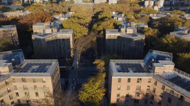 Sunlight illuminates Queensbridge Houses public housing development, condominiums with rooftop solar panels in Queens, New York City, urban development and renewable energy