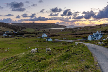 Die Orte Glendale und Fasach auf der Insel Isle of Skye mit einem Blick auf die Bucht Loch Pooltiel und im Hintergrund die Äußeren Hebriden nach Sonnenuntergang in Schottland