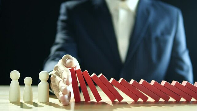 Hand of businessman stopping, prevent falling block, domino effect to safe family life, property, insurance from crisis. Concept of Risk Assessment, Crisis, Economic, Business Management, Inflation. 