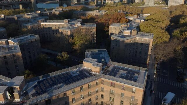 Autumn foliage enveloping Queensbridge Houses and Roosevelt Island residential structures, Queens, solar panel topped roofs, Queensboro Bridge framing Manhattan skyline