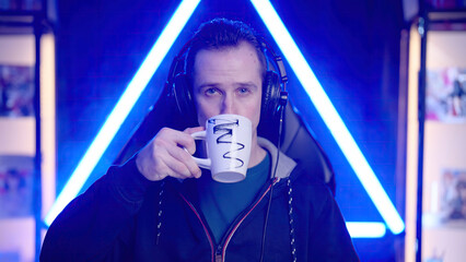 Male streamer looking at camera and drink a cup of coffee