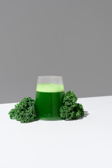 Batido de jugo de col rizada verde y hojas frescas de col rizada sobre fondo gris	
