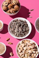 Pipas de girasol, semillas de chía, sésamo, nueces y pistachos. Frutos secos sobre un fondo rosa