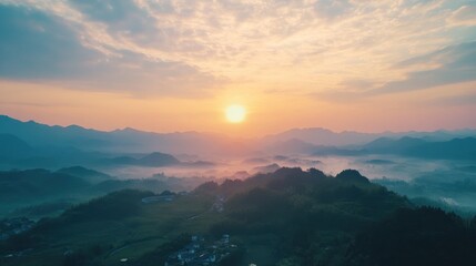 Obraz premium Breathtaking aerial view of a sunrise illuminating misty mountain landscape and a village