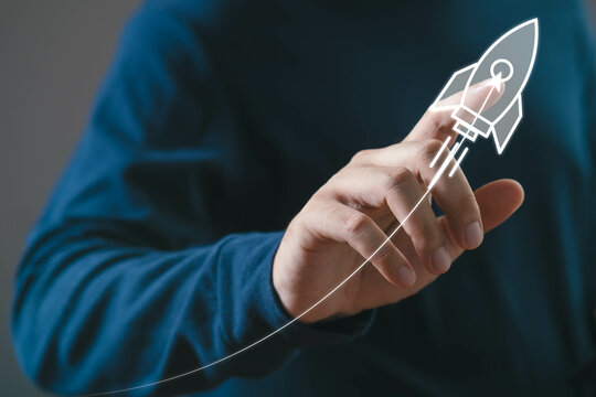 Innovative startup concept with hand drawing rocket launch symbolizing growth and success in business and technology sectors against blue background.