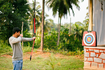 Young Indian man enjoying archery practice in the park.