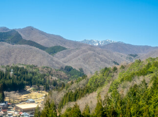 Landscape view of mountains and forests in rural area of Takayama, Japan, under clear blue sky in spring season