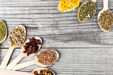 Herbal collection in wooden spoons: chamomile, calendula, dill and milk thistle seeds.Wooden Spoons with Dried Chamomile, Calendula, and Seeds on White Background. 
