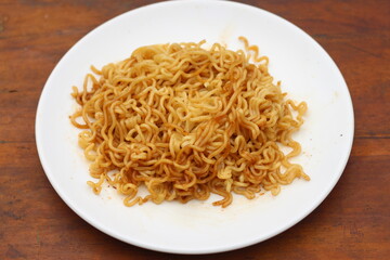 Top view of instant noodles spicy in white plate on wooden table background.