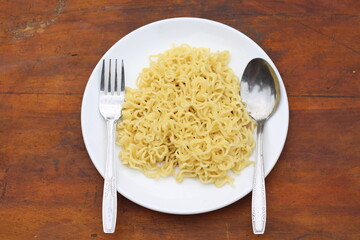 Top view of instant noodles spicy in white plate on wooden table background.