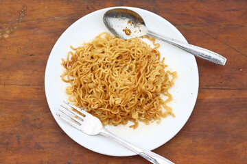 Top view of instant noodles spicy in white plate on wooden table background.