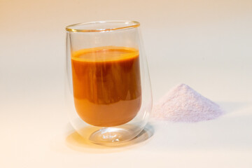 refreshing glass of Thai iced milk tea, served in a clear glass cup. The rich, vibrant orange color of the tea contrasts beautifully with the creamy milk at the bottom. A perfect blend