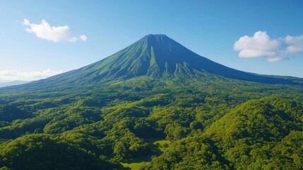 Fototapeta premium Majestic Mountian landscape of lush green forests under a clear blue sky with few clouds