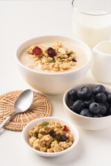 Oatmeal bowl with blueberries, granola, almonds and milk. Healthy breakfast concept.