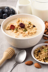 Oatmeal bowl with blueberries, granola, almonds and milk. Healthy breakfast concept.
