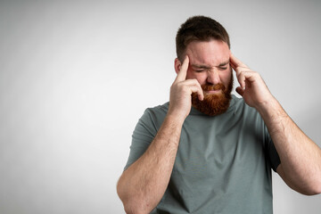 Young bearded guy freelancer suffering from headache after hard working day.