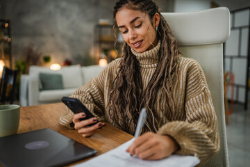 young woman work on clipboard and cellphone at home office