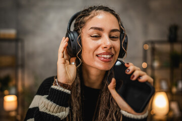 happy young woman listen music on headphones and sing at home
