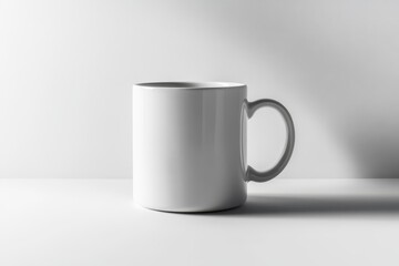 Fototapeta premium A minimalistic white mug is positioned on a light surface, casting a subtle shadow, emphasizing its smooth curves and clean design.