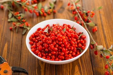 fresh ripe red goji berries in a bowl on a wooden table