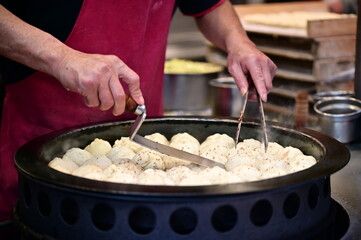 This photo captures the precise process of preparing shuijianbao, a beloved Taiwanese street food with a crispy golden crust and juicy filling. Perfectly cooked for a savory bite.