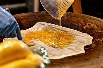 Roti. Close-up of beaten eggs poured onto dough in process of preparing sweet dessert on heated surface. Vibrant colors enhance delicious appearance and convey careful preparation of street food