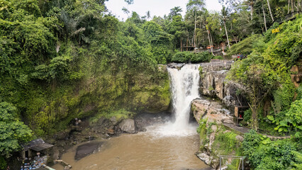 Tegenungan Waterfall, a picturesque Bali attraction, is surrounded by dense jungle and vibrant...