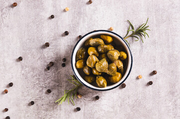 Close up of pickled capers with spices in a bowl and in a jar on the table top view