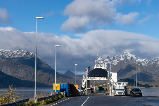 Digermulen, Norway-21 September 2024; Ferry boat at the terminal in Digermuler harbor with mountains of Trollfjord (Trollfjorden) covered in first dusting of snow on Lofoten island chain archipelag