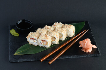 A set of sushi rolls on a wooden board and banana leaf, served with soy sauce, wasabi, ginger, and chopsticks. Perfect for an Asian restaurant menu.