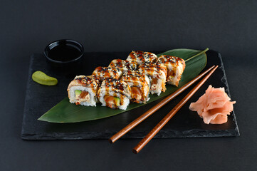 A set of sushi rolls on a wooden board and banana leaf, served with soy sauce, wasabi, ginger, and chopsticks. Perfect for an Asian restaurant menu.