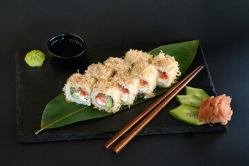 A set of sushi rolls on a wooden board and banana leaf, served with soy sauce, wasabi, ginger, and chopsticks. Perfect for an Asian restaurant menu.