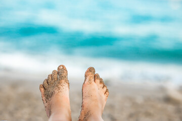 Cute little girl in a hat and striped swimsuit lies on a sun lounger and sunbathes on the beach in summer. Holiday vacation with children.