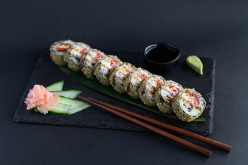 A set of sushi rolls on a wooden board and banana leaf, served with soy sauce, wasabi, ginger, and chopsticks. Perfect for an Asian restaurant menu.