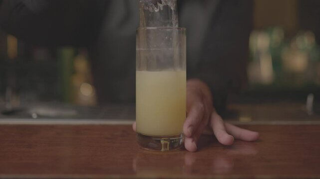 Close-up of a bartender serving a freshly made cocktail in a glass at a modern bar