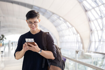close up young asian man smile and looking while holding passport ,ticket and smartphone in airport...
